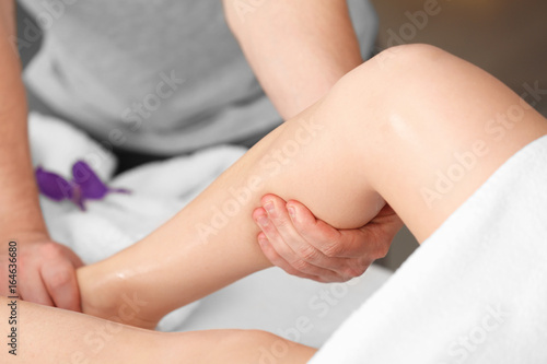 Young woman having legs massage in spa salon, closeup