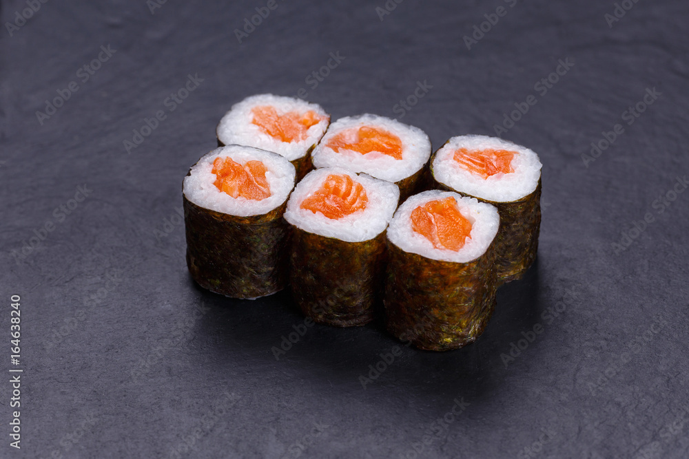 Traditional sushi rolls with raw salmon served on black slate, Japanese cuisine. Traditional sushi rolls with raw salmon served on black slate, Japanese cuisine.