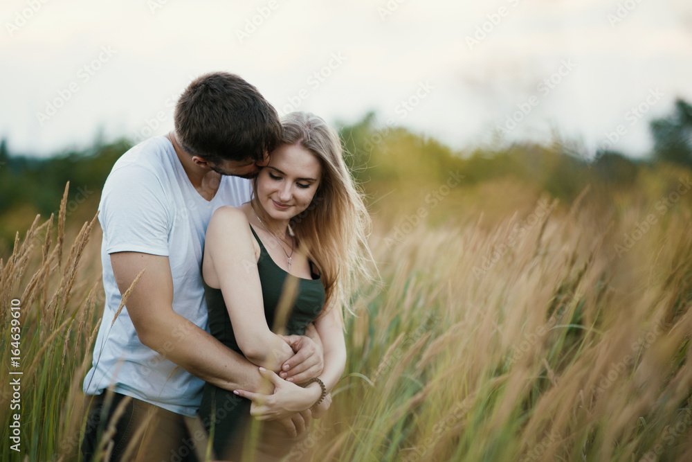 Romantic Couple at Sunset. Two people in love at sunset or sunrise. Man and woman on field Romantic Couple at Sunset. Two people in love at sunset or sunrise. Man and woman on field