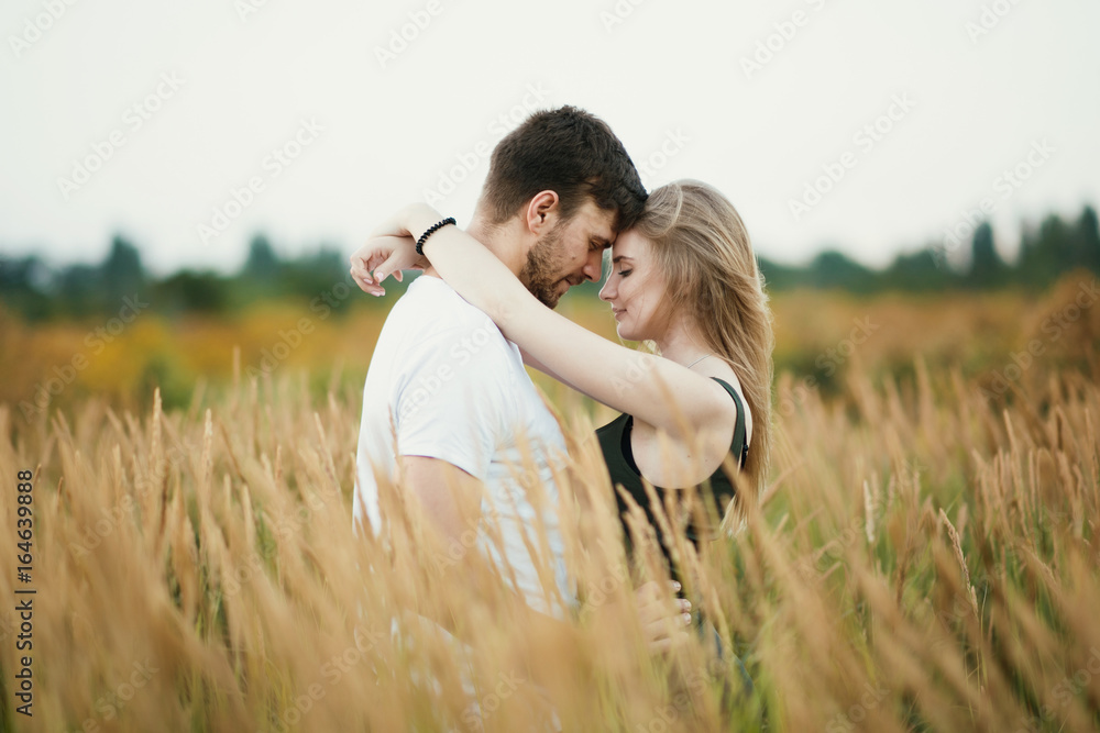 Romantic Couple at Sunset. Two people in love at sunset or sunrise. Man and woman on field Romantic Couple at Sunset. Two people in love at sunset or sunrise. Man and woman on field