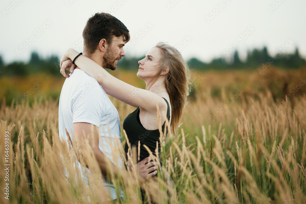Romantic Couple at Sunset. Two people in love at sunset or sunrise. Man and woman on field Romantic Couple at Sunset. Two people in love at sunset or sunrise. Man and woman on field