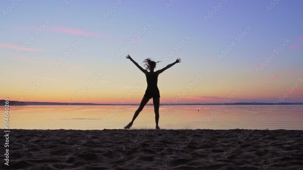 Young woman is runing along the beach on a sunset background Young woman is runing along the beach on a sunset background