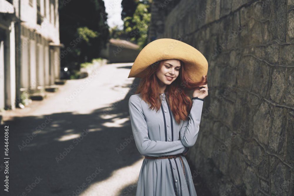 Young beautiful woman in white dress and hat walking in the city