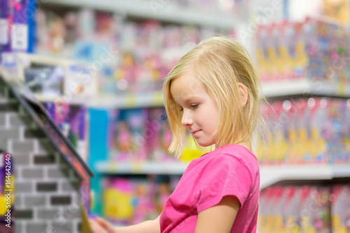 Adorable girl in pink explore toys in kids supermarket