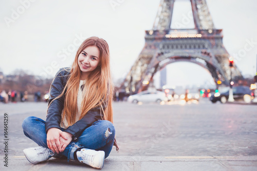 smiling happy beautiful woman tourist in Paris looking at camera, portrait of caucasian girl near Eiffel Tower