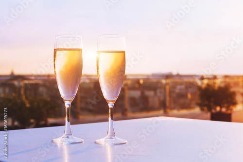 two glasses of champagne at rooftop restaurant with view of city skyline, luxury romantic dinner for couple