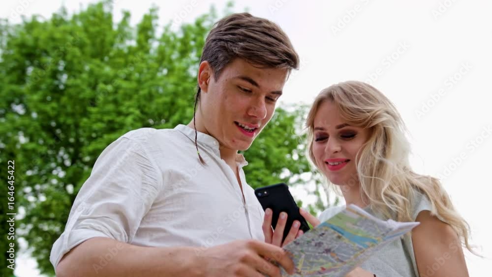 A young blonde couple using a smapthone outdoors. Looking for directions. Soft focus. Medium shoot A young blonde couple using a smapthone outdoors. Looking for directions. Soft focus. Medium shoot