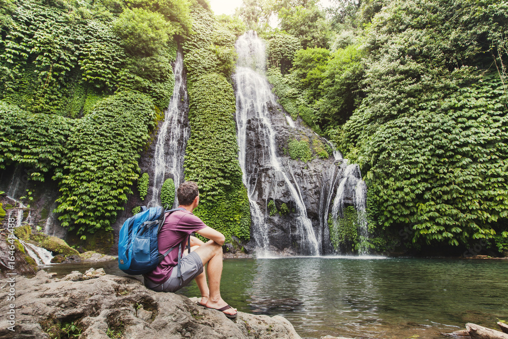 Fototapeta premium tourist backpacker looking at waterfall in Bali