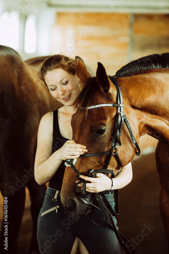 Fototapeta Naklejka Na Ścianę i Meble -  Woman hugging brown horse in stable