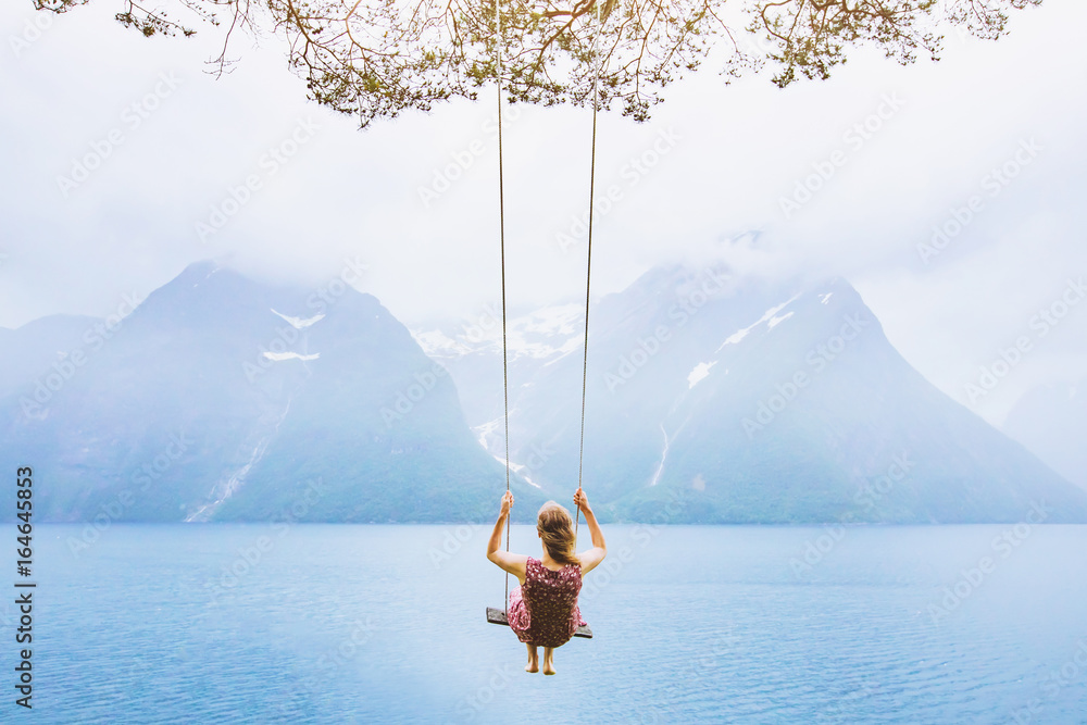 Naklejka premium koncepcja marzeń, piękna młoda kobieta na huśtawce w Norwegii fiordowej, inspirujący krajobraz