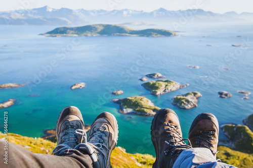 trekking shoes on feet of couple of travelers hikers sitting on top of the mountain in Norway with the beautiful view, trekkers selfy with norwegian landscape