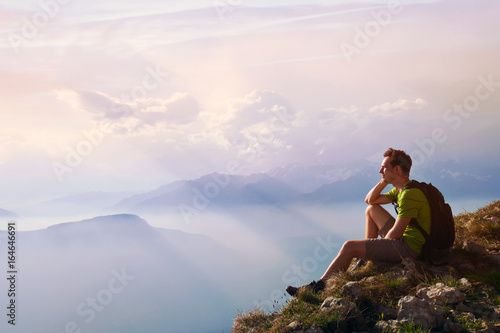 man sitting on top of mountain, achievement or opportunity concept, hiker looking forward on beautiful panoramic landscape