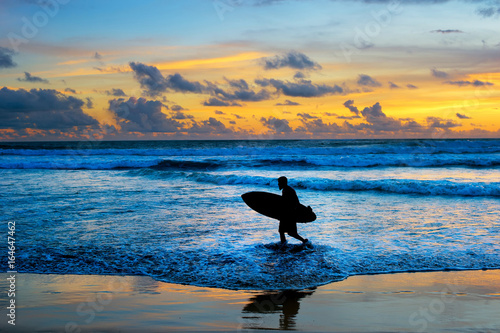 Surfer with surfboard at sunset