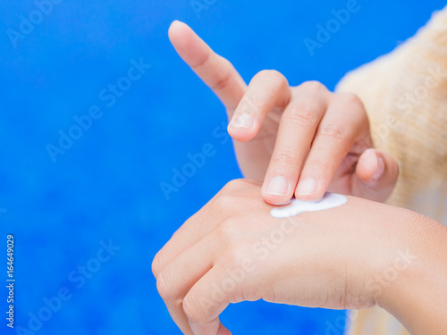 Woman hand apply sunscreen   sunblock by the swimming pool. Vacation and relaxation  summer travel concept.