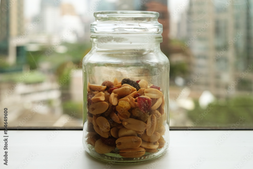 Jar of salty peanuts, rasin, berries, dried fruits with blurry background Jar of salty peanuts, rasin, berries, dried fruits with blurry background