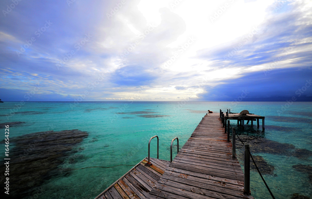 Wooden deck overa clear blue lagoon with coral reef Wooden deck overa clear blue lagoon with coral reef