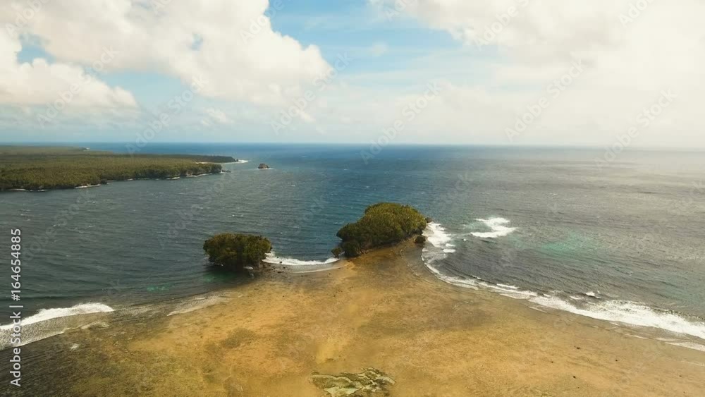 Aerial view: sea and the tropical island with rocks, beach and waves. Coastline of the tropical island Siargao with the mountains and the rainforest on a background of ocean with big waves. Seascape Aerial view: sea and the tropical island with rocks, beach and waves. Coastline of the tropical island Siargao with the mountains and the rainforest on a background of ocean with big waves. Seascape