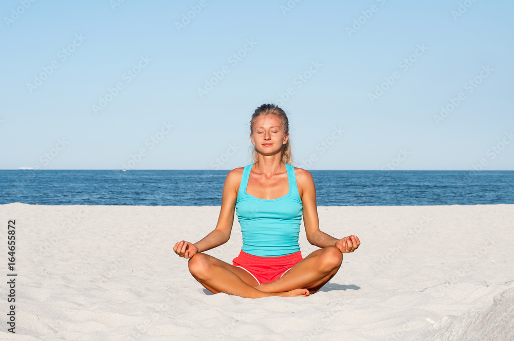 Woman practicing yoga on the beach