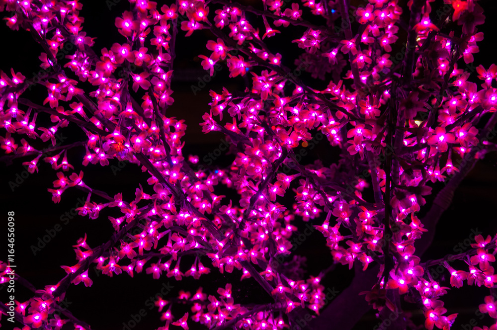 Neon artificial red flowers on a black background