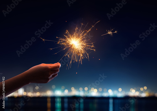 Female hand holding a burning sparkler photo