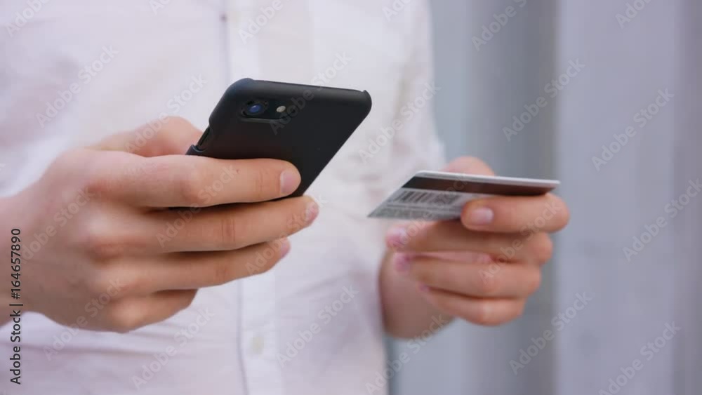 A young man using a smapthone outdoors. Mobile banking. Soft focus. Close-up shoot A young man using a smapthone outdoors. Mobile banking. Soft focus. Close-up shoot