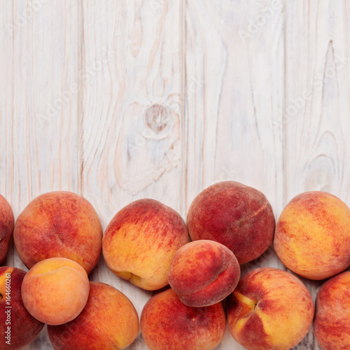 Ripe tasty peaches on a light wooden background.