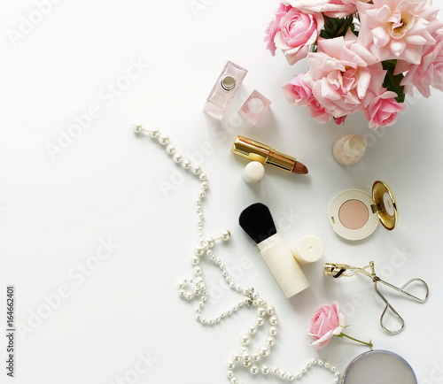 Flat lay, top view feminine desk, workspace , female make up accessories and bouquet roses.Beauty blog concept.Copy space
