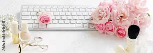 Flat lay, top view office feminine desk, female make up accessories, workspace with laptop and bouquet roses.Beauty blog concept.Banner