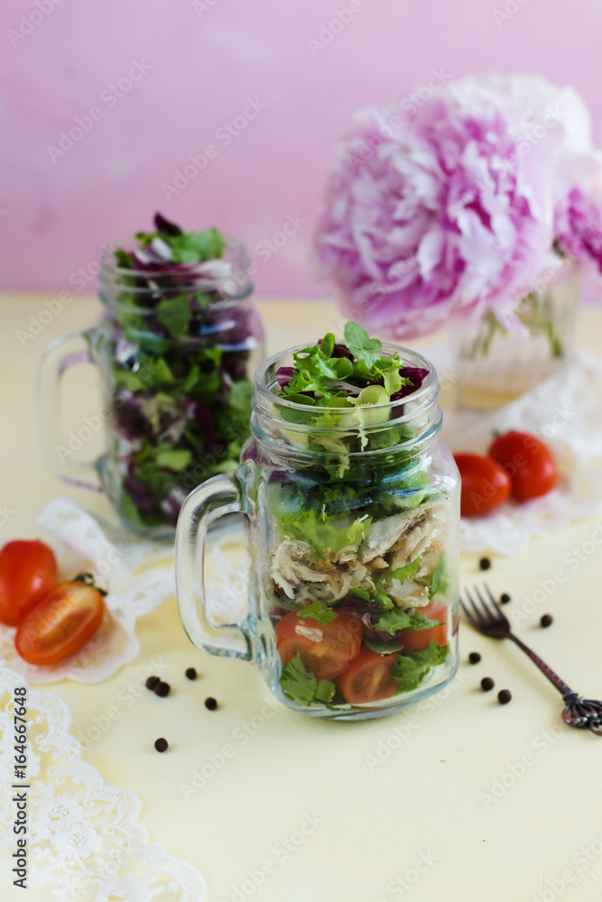 Summer salad with greens in a mug on a pink background