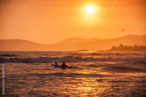 Beautiful sunset with surfers in the ocean waves