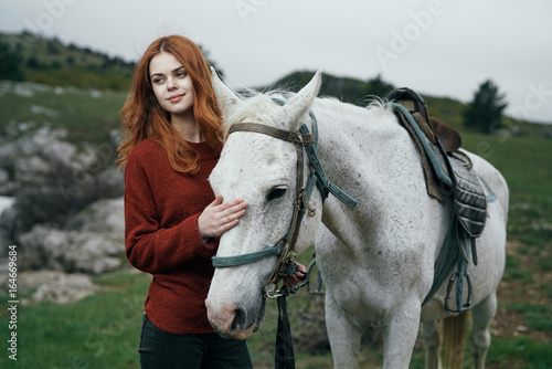 Young beautiful woman walks on nature with her horse