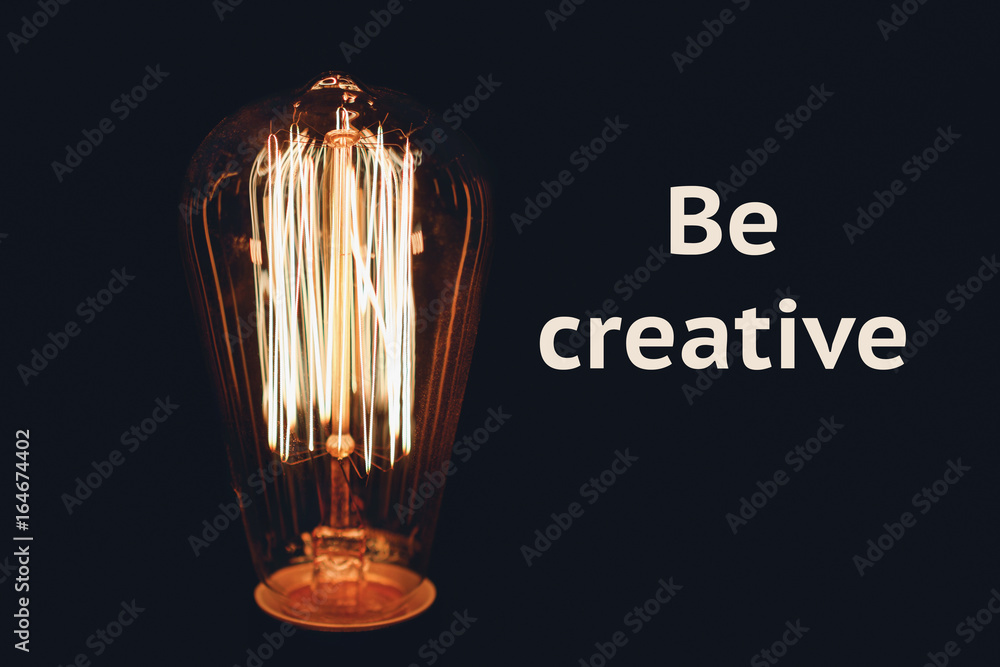 Inscription Be creative on the image of retro bulb on a black background. Creativity concept.