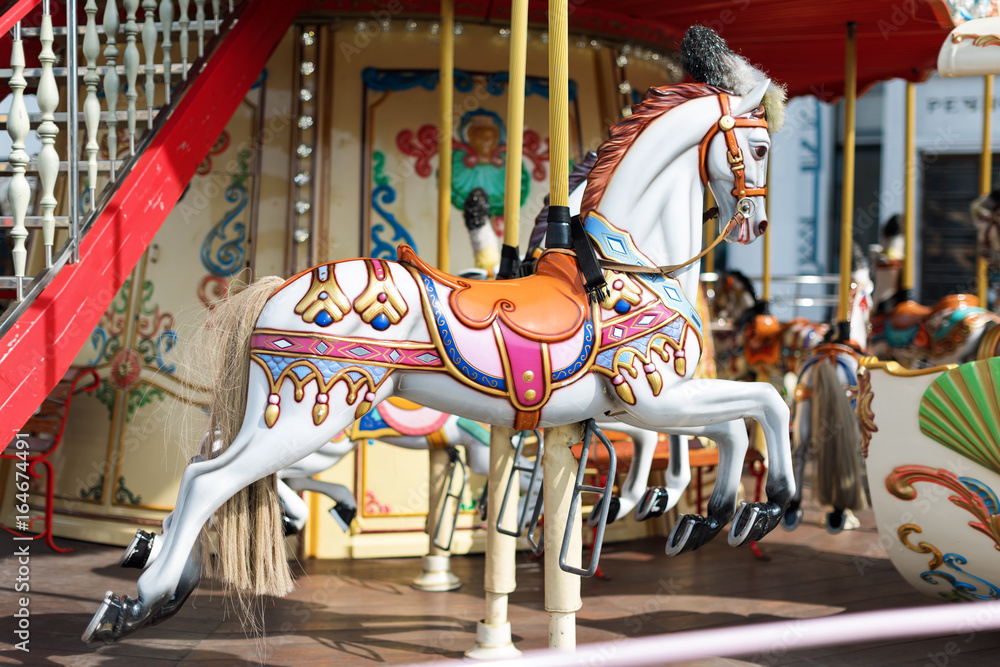 Horses on a carnival Merry Go Round. Old French carousel in a holiday park. Big roundabout at fair in amusement park.