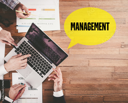 BUSINESS TEAM WORKING IN OFFICE WITH MANAGEMENT SPEECH BUBBLE ON DESK photo