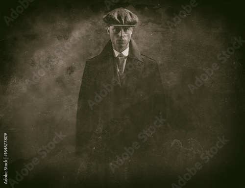 Antique wet plate photo of threatening 1920s english gangster in smoky room.