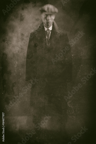 Antique wet plate photo of threatening 1920s english gangster in smoky room.