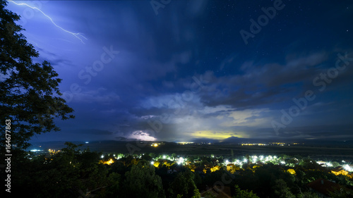 Picture of stormy sky with thunders and clouds during nigh over small city