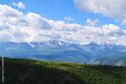 White peaks of North-Chuysky ridge and green meadows of Kurai steppe in Altai mountains. Altay Region, Siberia, Russia.
