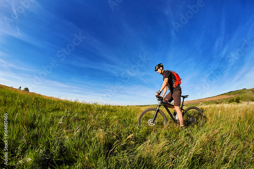 Young cyclist riding mountain bicyclist against beautiful sunset in the countryside.
