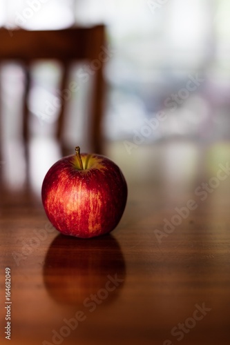 Bright red apple on a reflective wooden table photo