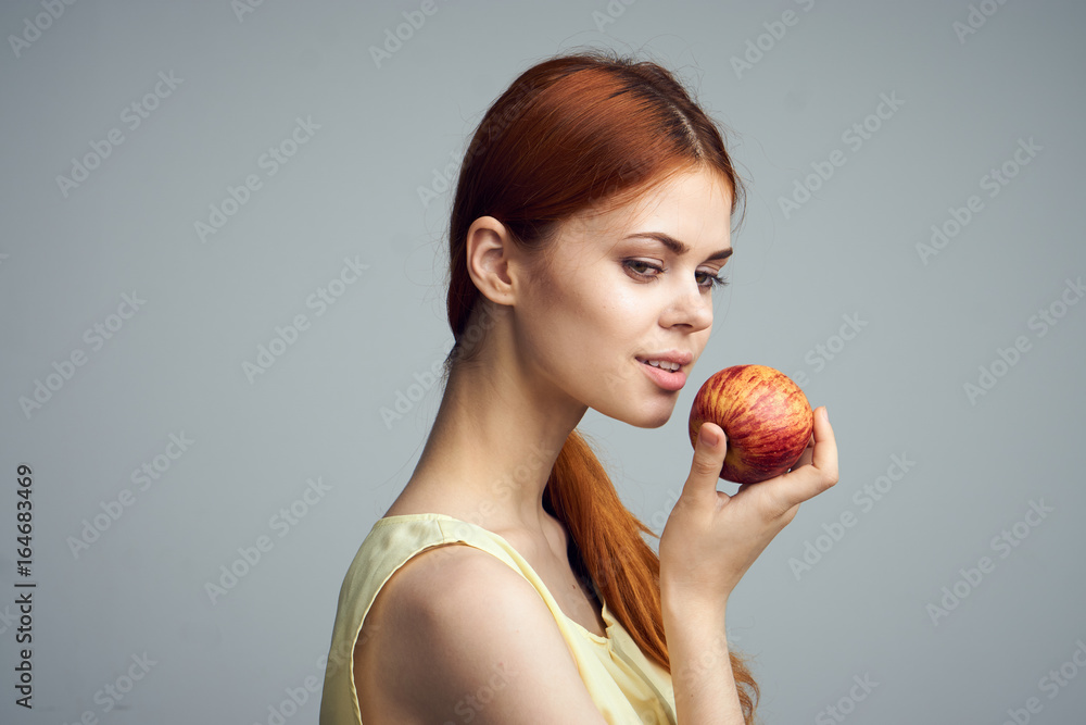 Young beautiful woman on a gray background holds an apple Young beautiful woman on a gray background holds an apple