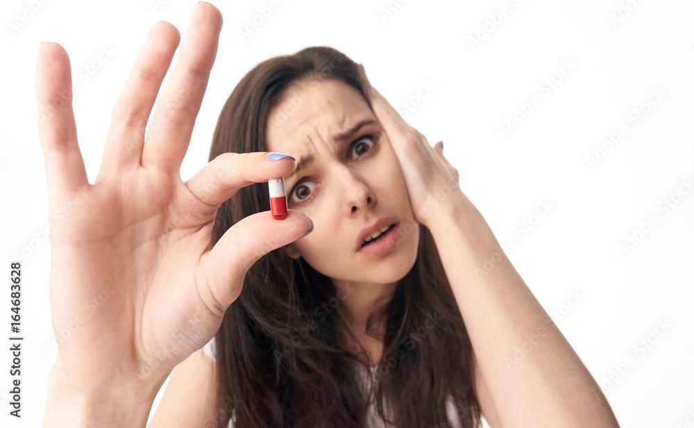 Young beautiful woman on white background isolated on white holding a pill Young beautiful woman on white background isolated on white holding a pill