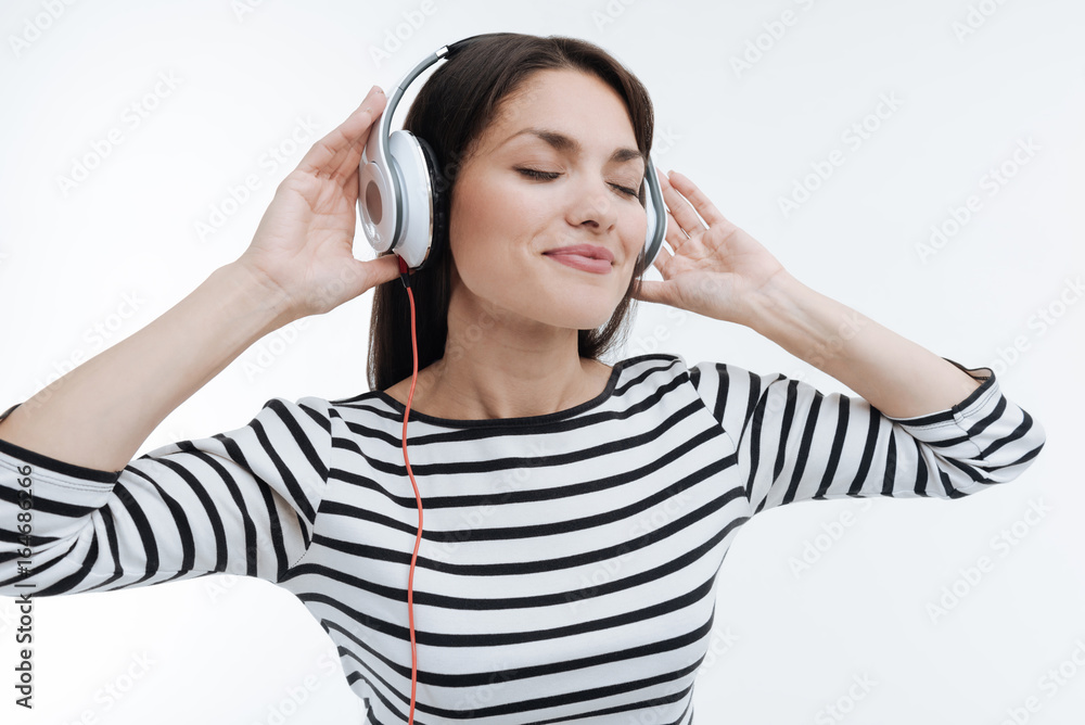 Positive delighted brunette putting hands on headphones Positive delighted brunette putting hands on headphones