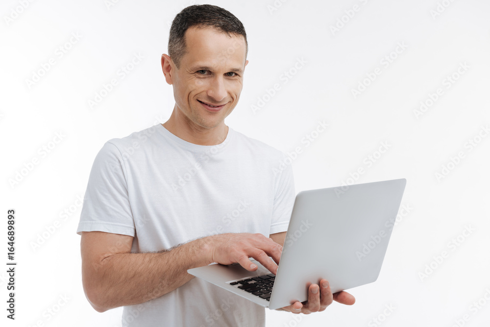 Positive delighted man working with laptop Positive delighted man working with laptop
