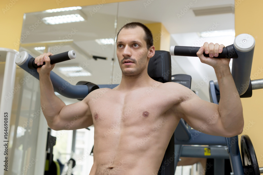 bodybuilder man shoulder muscles exercise with machine in fitness club bodybuilder man shoulder muscles exercise with machine in fitness club