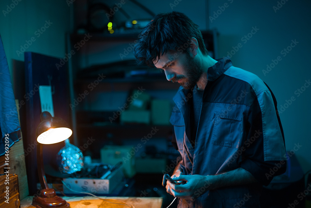 Bearded man mechanic in garage.Man in a robe,notebook,laptop,man on service station,worker