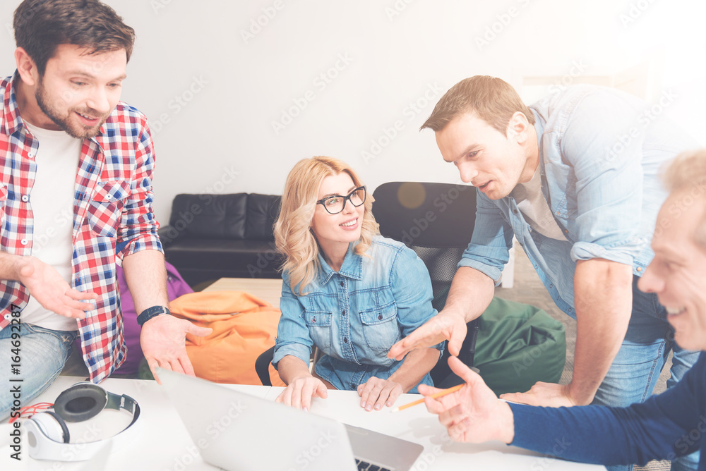 Obraz premium Positive colleagues using laptop in the office