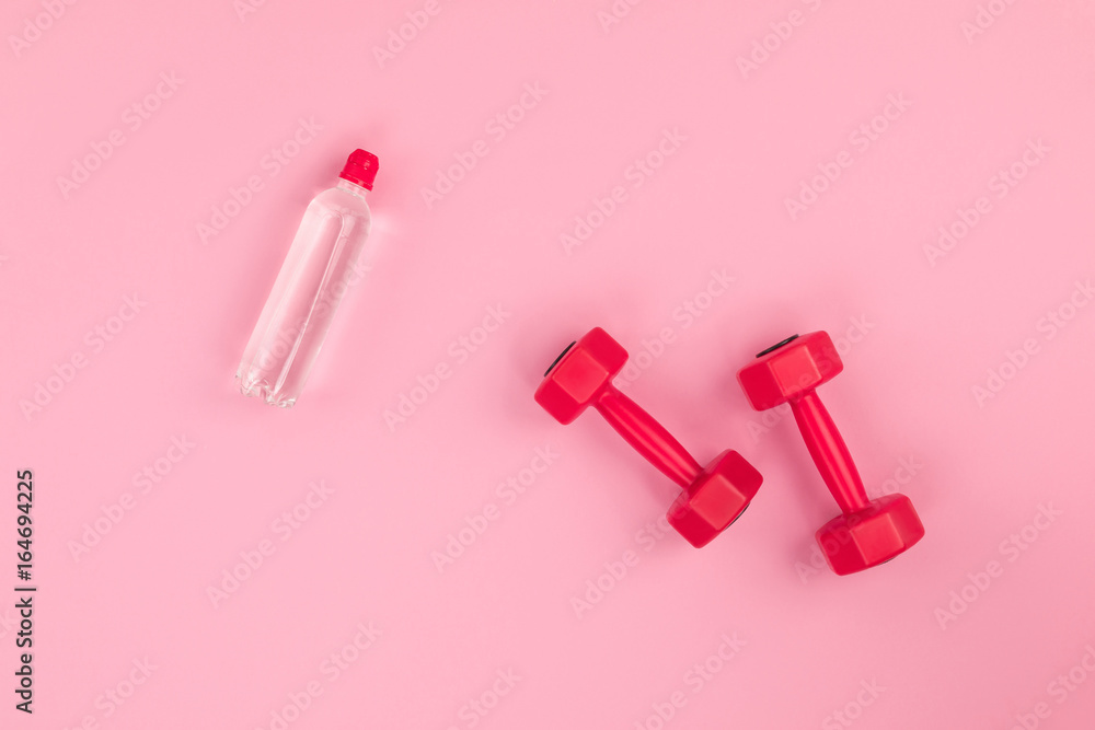 top view of red dumbbells and bottle of water isolated on pink