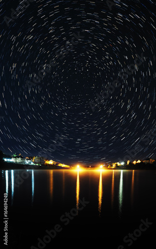 Night lake with reflection and star trails over it panorama vertical