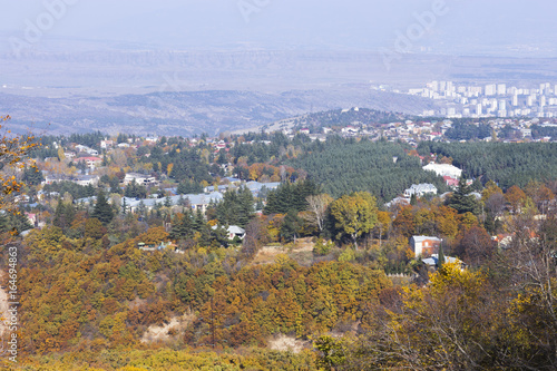 Autumn view of the city and park at the foot of the mountains.